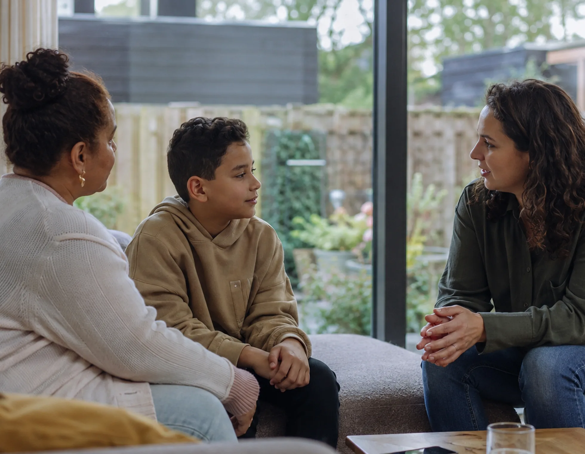 Een ouder, een kind en een ambulant begeleider in gesprek